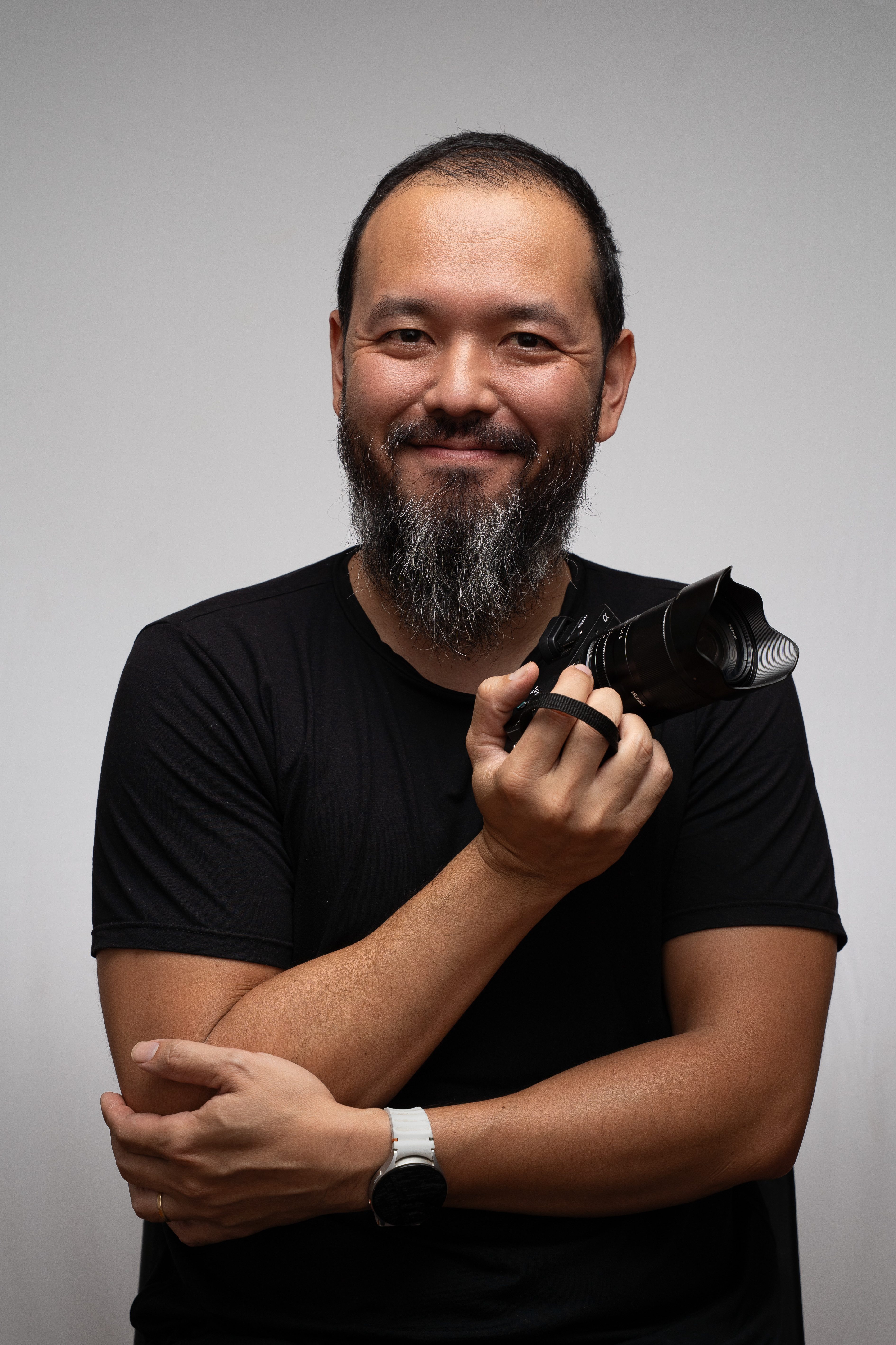 Fotógrafo da Tavalá Fotografia segurando câmera, sorrindo